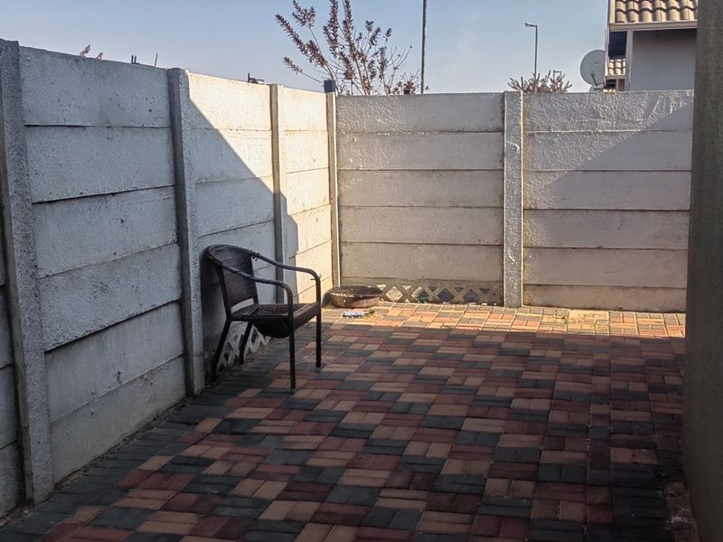 A private paved patio area enclosed by precast concrete boundary walls, offering a functional outdoor space for relaxation.