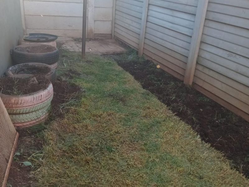 A small rear garden area enclosed by precast concrete walling, featuring a lawn and a fixed washing line.