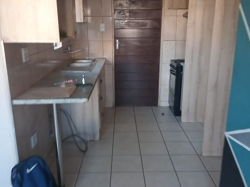 A functional kitchen featuring tiled flooring, laminate countertops, built-in cabinetry, and a freestanding stove, offering a practical layout for daily meal preparation.