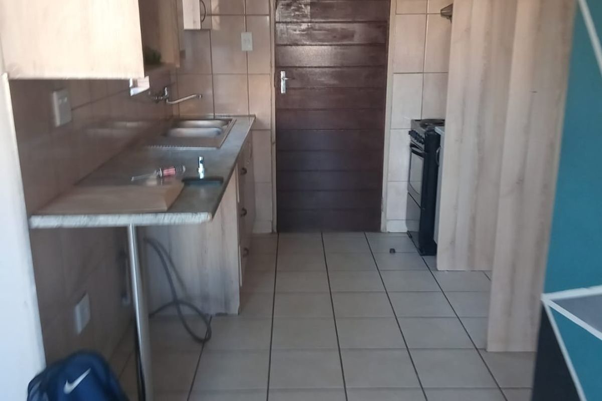 A functional kitchen featuring tiled flooring, laminate countertops, built-in cabinetry, and a freestanding stove, offering a practical layout for daily meal preparation.