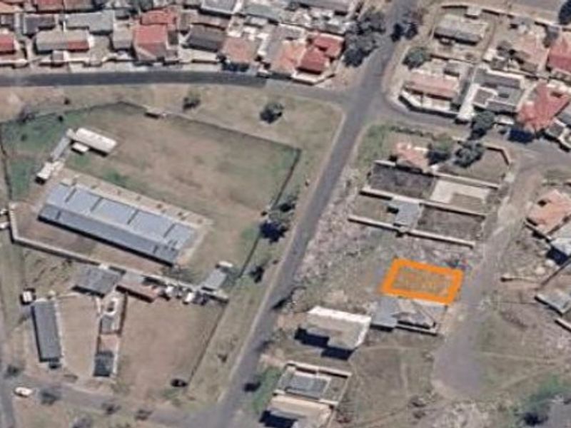 An aerial view of a vacant residential plot highlighted in an urban neighborhood setting.