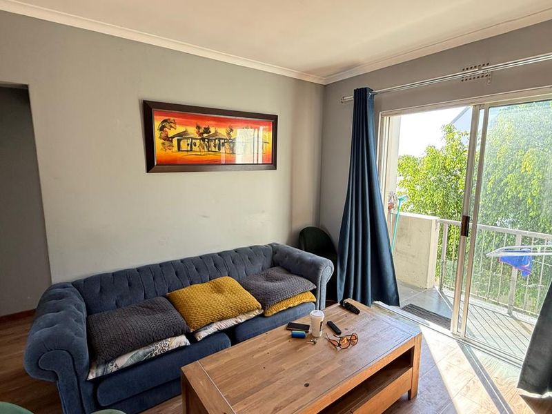 Living room featuring laminate flooring and a sliding glass door providing access to an outdoor balcony area.