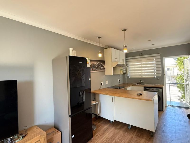 Open-plan living and kitchen area featuring a functional kitchenette with wooden countertops, electric hob, and direct access to an outdoor space.