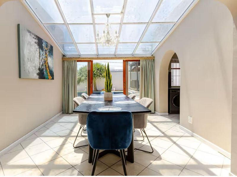 Bright dining room featuring a glass roof, tiled flooring, and an arched entryway, providing a seamless transition to the outdoor area.