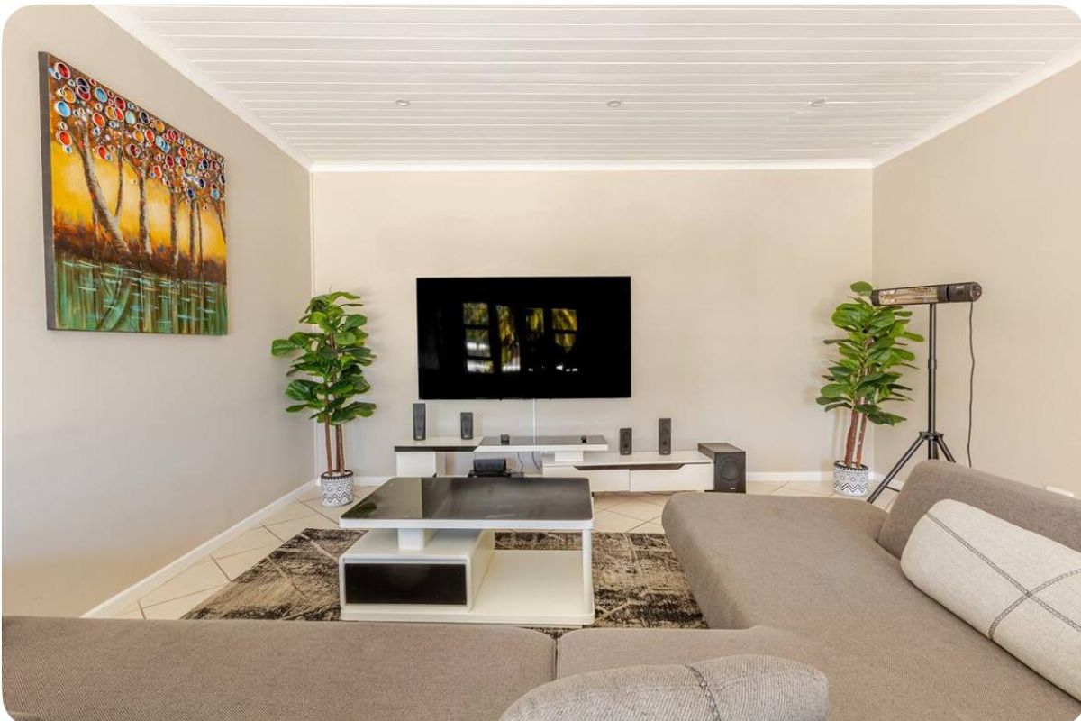 A well-maintained living room featuring tiled flooring and a white tongue and groove ceiling with recessed lighting.