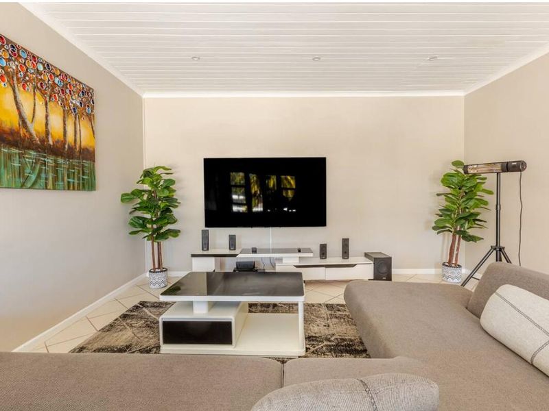 A well-maintained living room featuring tiled flooring and a white tongue and groove ceiling with recessed lighting.
