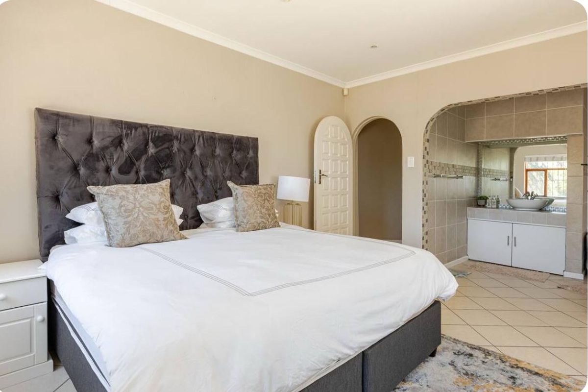 Spacious bedroom featuring an arched entryway leading to an en-suite bathroom area with a built-in vanity and tiled flooring.