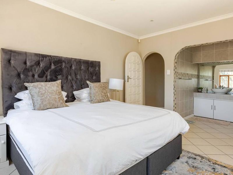 Spacious bedroom featuring an arched entryway leading to an en-suite bathroom area with a built-in vanity and tiled flooring.