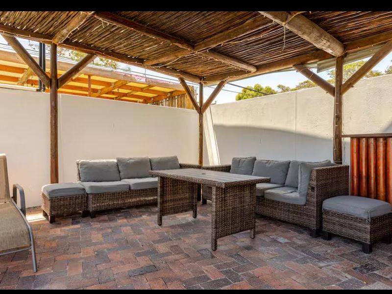 A covered outdoor patio area featuring a rustic thatched roof, timber support structure, and durable brick paving, ideal for outdoor entertaining.