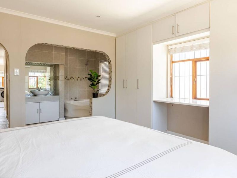 Spacious bedroom featuring built-in cupboards, a dedicated vanity area, and an open-plan en-suite bathroom with a built-in bathtub.