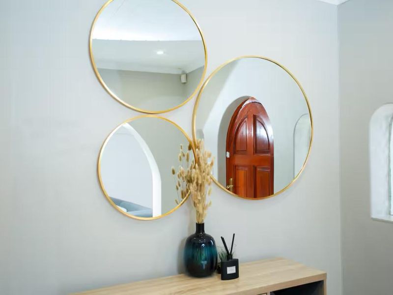 A close-up view of a wall featuring decorative circular mirrors and an arched window detail.