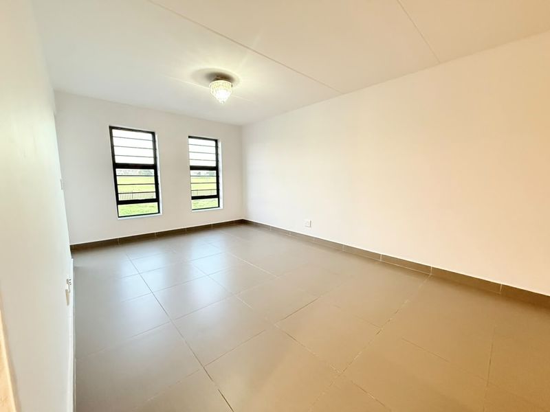 A bright, empty bedroom featuring neutral tiled flooring, large windows with security bars, and a clean, minimalist aesthetic ready for personalization.