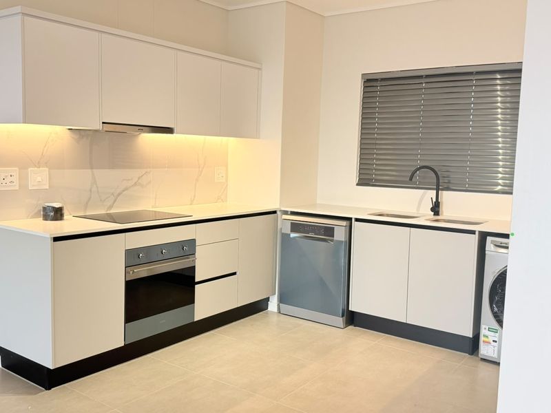 Modern kitchen featuring sleek white cabinetry, quartz countertops, integrated appliances, and high-quality finishes in a clean, minimalist design.