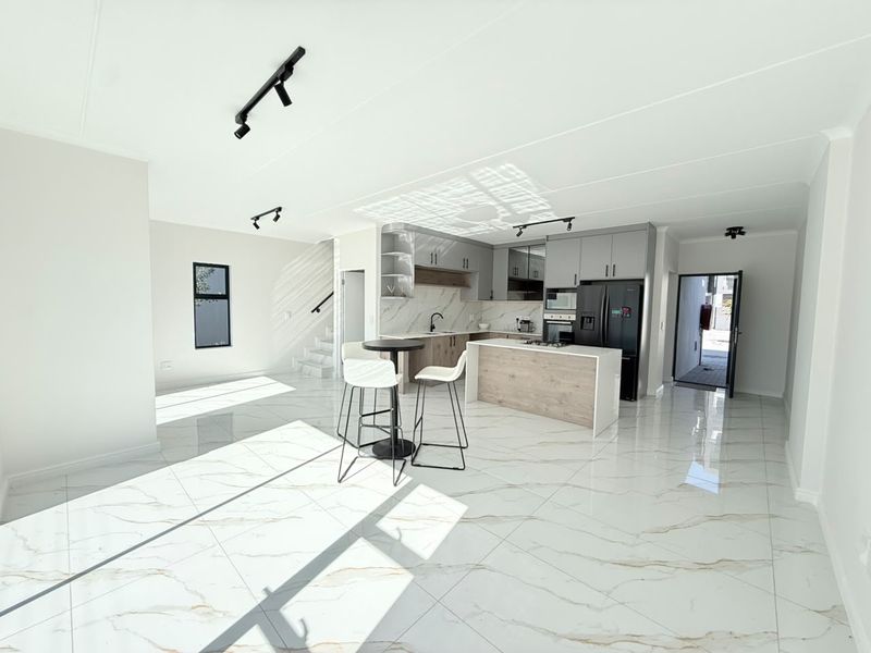Modern open-plan living area featuring high-gloss marble-look floor tiles, a contemporary kitchen with island, built-in appliances, and sleek cabinetry.