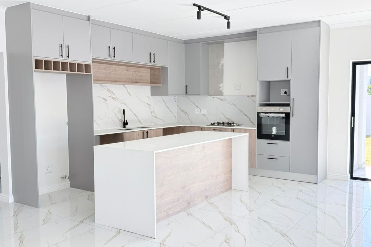 Modern kitchen featuring grey and wood-tone cabinetry, a central island, stone countertops, marble-look backsplash, and built-in oven, with high-quality porcelain floor tiles.