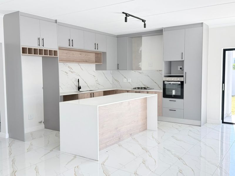 Modern kitchen featuring grey and wood-tone cabinetry, a central island, stone countertops, marble-look backsplash, and built-in oven, with high-quality porcelain floor tiles.