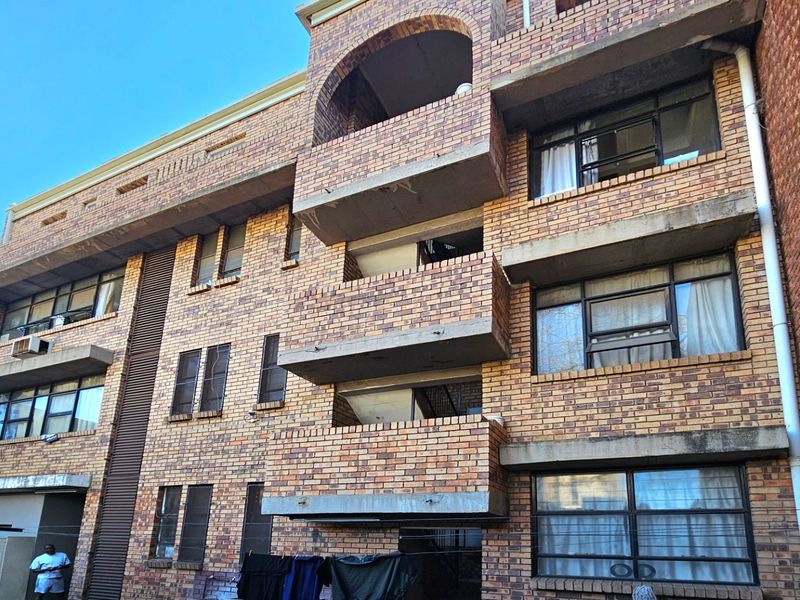 Rear elevation of a multi-story commercial or residential building featuring face brick construction, integrated concrete balconies, and steel-framed windows.