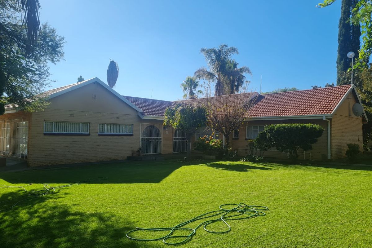 A view of the rear elevation of the house featuring a brick facade, tiled roof, and a spacious lawn area.