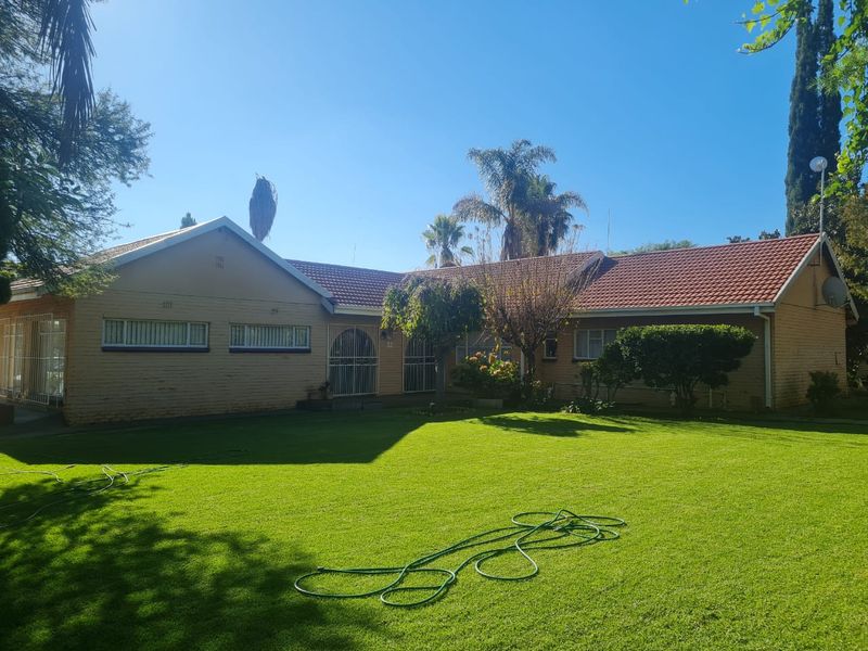 A view of the rear elevation of the house featuring a brick facade, tiled roof, and a spacious lawn area.