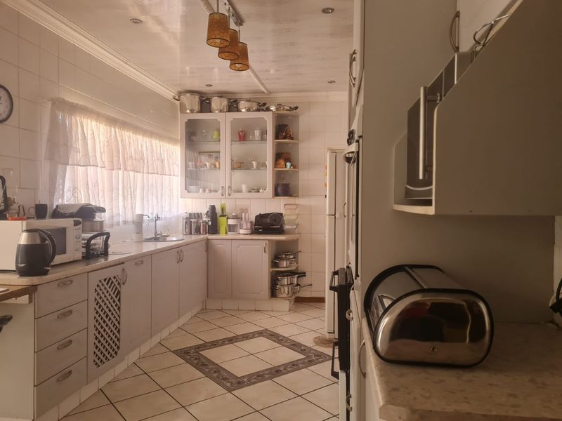 A functional kitchen featuring ample built-in cabinetry, tiled flooring with decorative inlay, and a tiled backsplash, offering a classic layout with good storage space.
