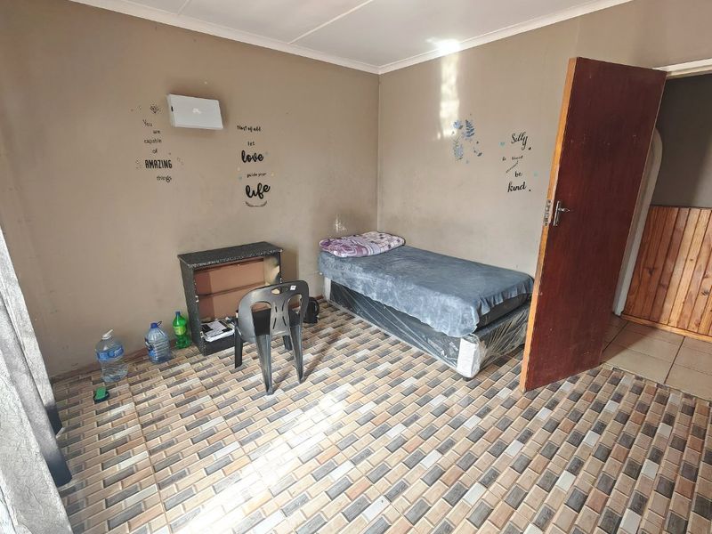 A bedroom featuring tiled flooring and a timber door, requiring cosmetic updates to the wall finishes to improve the overall aesthetic.