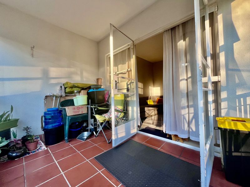 A functional balcony area featuring tiled flooring and double glass doors providing access to the interior living space.