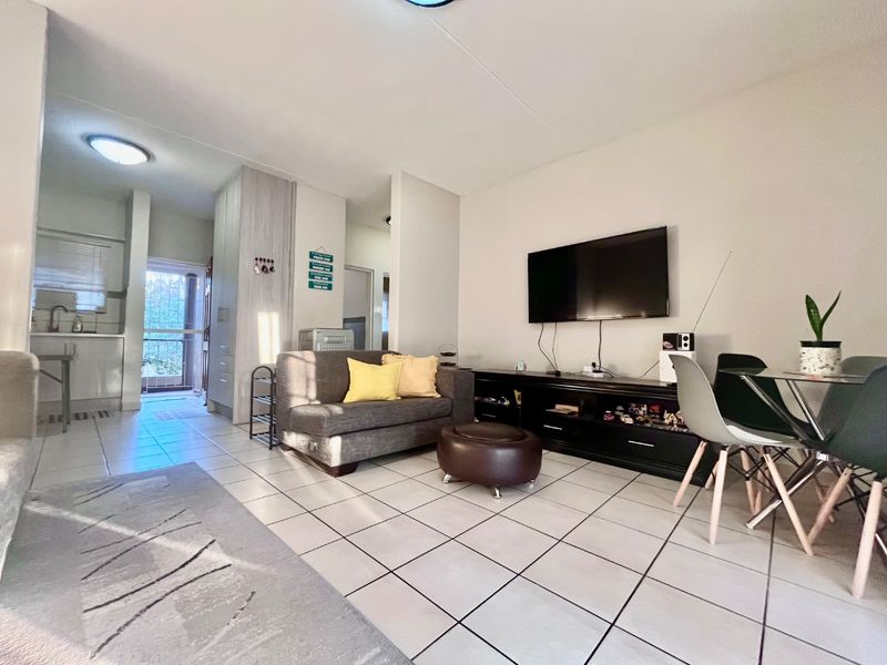Open-plan living area featuring tiled flooring and integrated kitchen access, providing a functional and connected layout for modern apartment living.