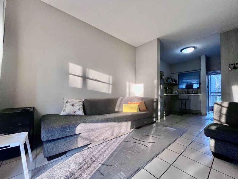 Open-plan living area featuring tiled flooring and a connected kitchen space with built-in cabinetry and sink.