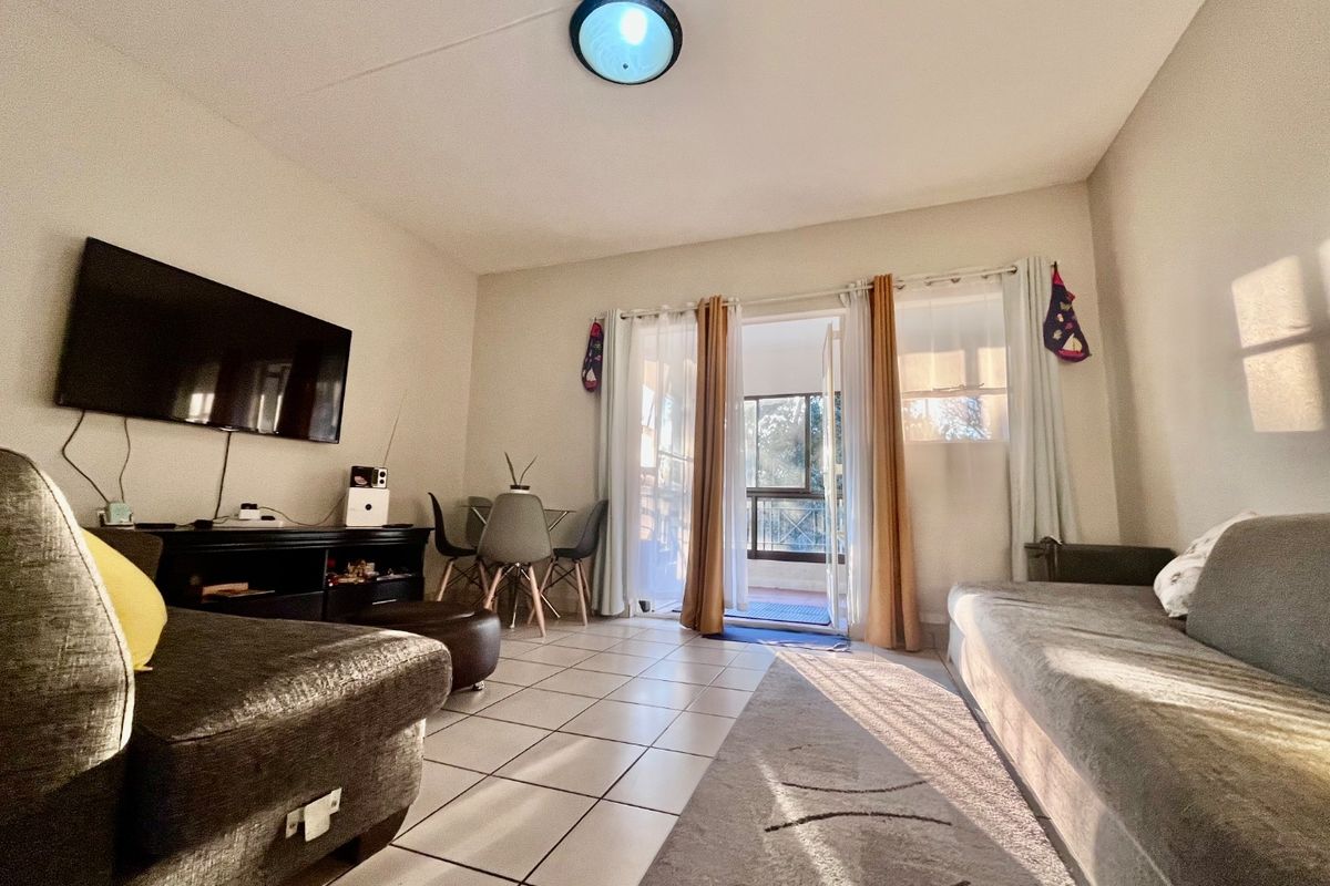 A living room featuring tiled flooring and a sliding glass door providing access to an outdoor balcony area.
