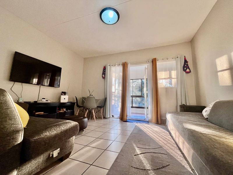 A living room featuring tiled flooring and a sliding glass door providing access to an outdoor balcony area.