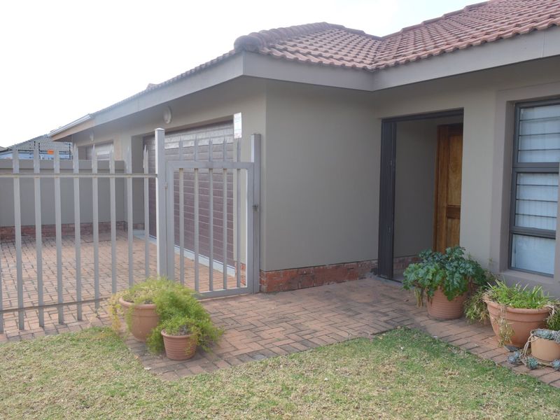 Front exterior view of a townhouse featuring a tiled roof, paved driveway, secure metal gate, and a private entrance.
