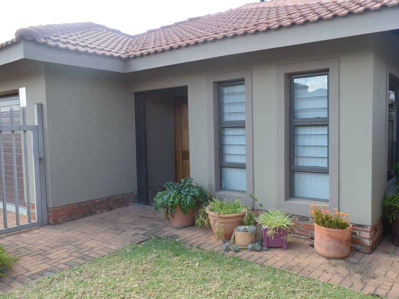 Front elevation of a townhouse featuring a tiled roof, brick paving, and a secure entrance with a timber door and aluminium window frames.