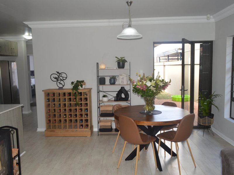 Open plan dining area featuring laminate flooring, modern pendant lighting, and direct access to the rear patio through a glass door.