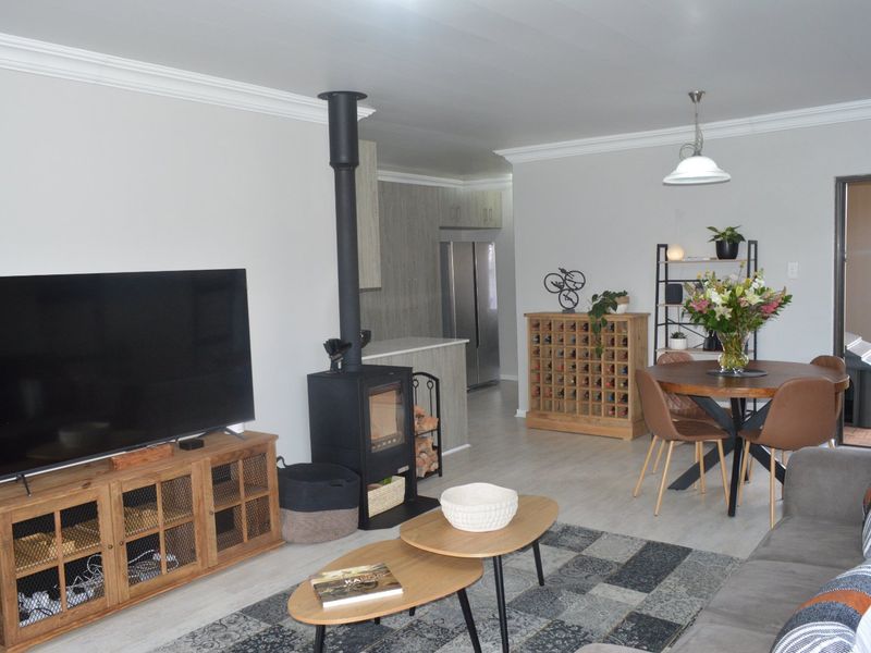 Open-plan living and dining area featuring a modern freestanding fireplace, light laminate flooring, and decorative cove cornicing.