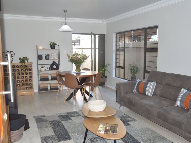 Open-plan living and dining area featuring tiled flooring, coving, and large windows with security bars, providing access to the exterior.