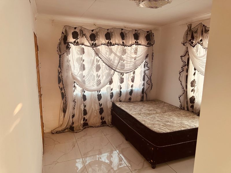 A bedroom featuring tiled flooring and a ceiling light fixture, providing a functional space ready for personalization.