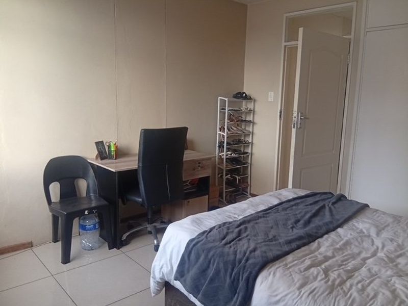 A functional bedroom featuring tiled flooring and built-in cupboard storage space.
