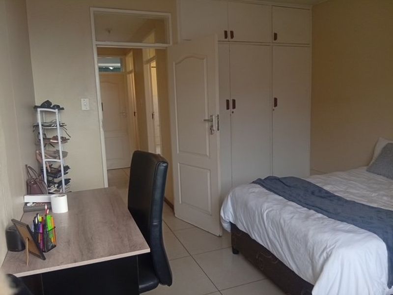 A bedroom featuring built-in cupboards and tiled flooring, with direct access to the hallway.