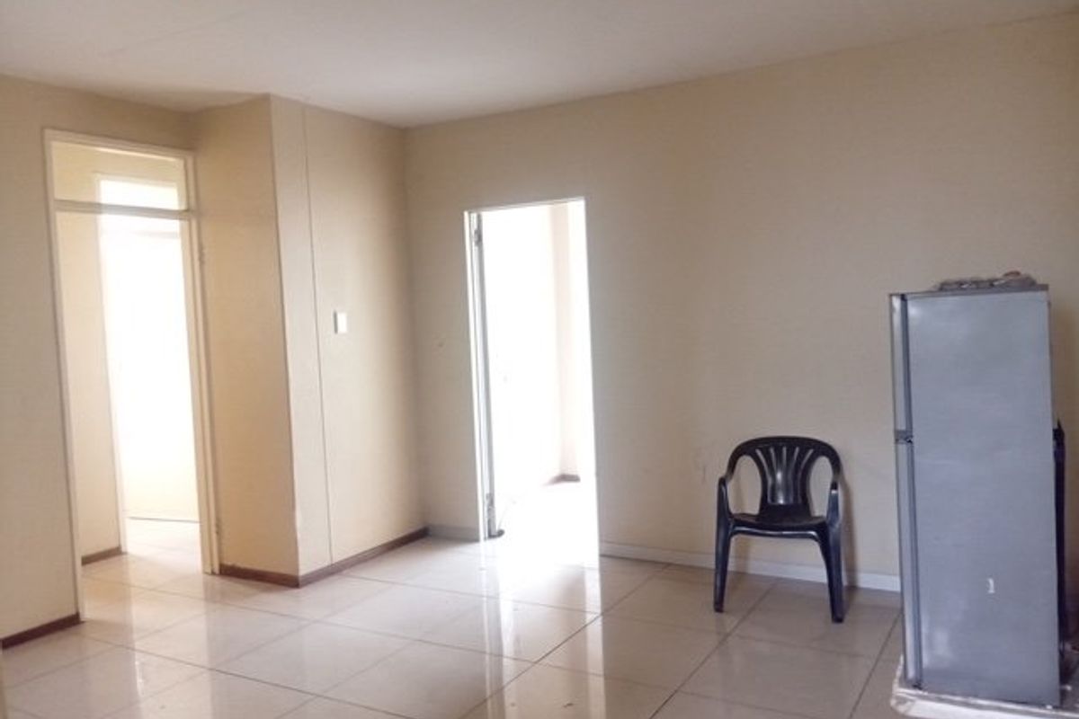 An empty living area featuring neutral walls and tiled flooring, providing a blank canvas for interior design and furniture placement.