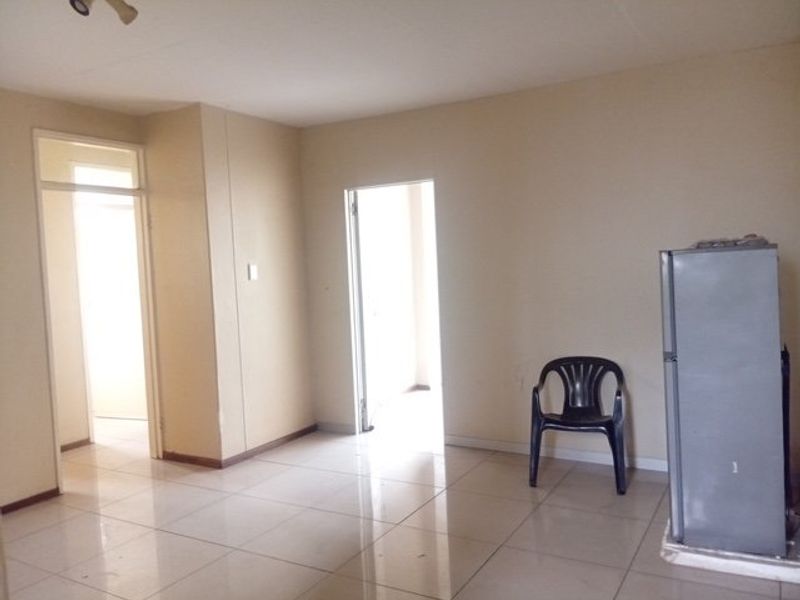 An empty living area featuring neutral walls and tiled flooring, providing a blank canvas for interior design and furniture placement.