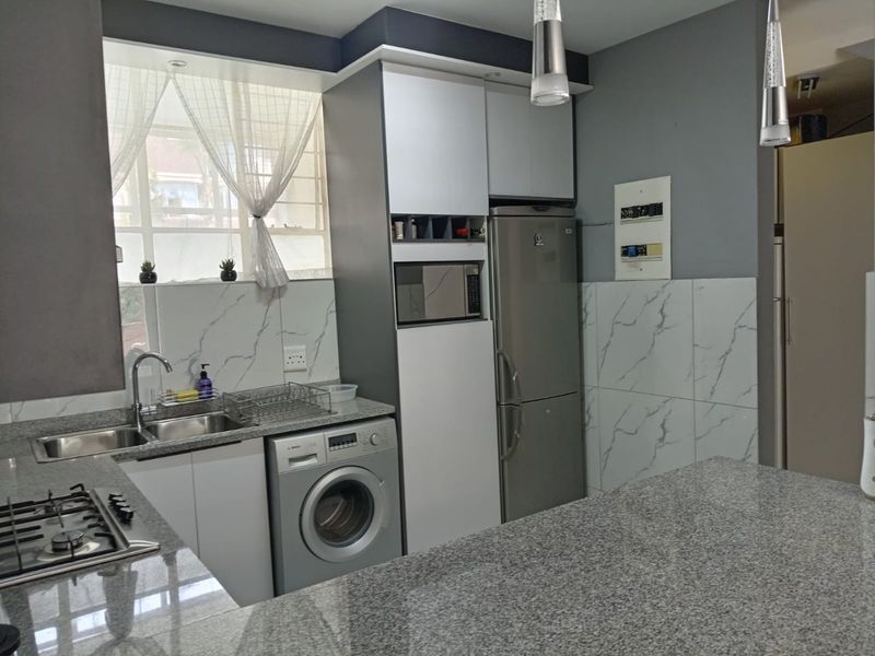 Modern kitchen featuring granite countertops, marble-look wall tiles, built-in cabinetry, gas hob, and integrated appliances in a clean, contemporary layout.