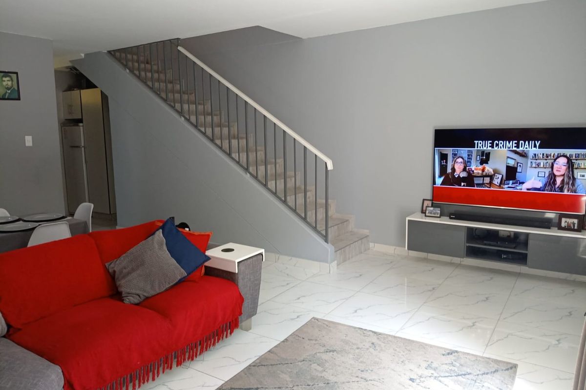 Open-plan living area featuring modern white tiled flooring and a central staircase with a metal balustrade.