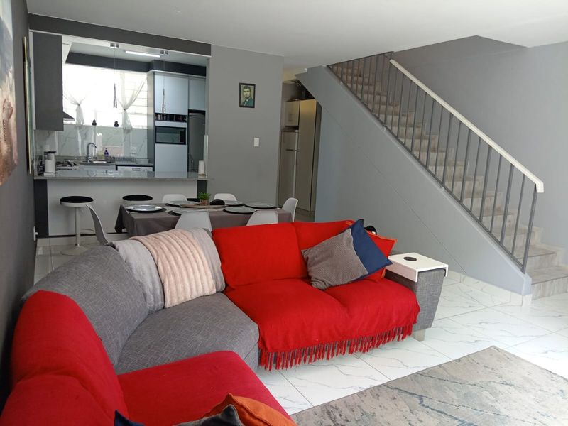 Open-plan living area featuring a modern kitchen with granite countertops, tiled flooring, and a staircase leading to the upper level.