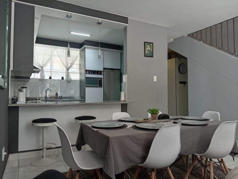 Open plan kitchen and dining area featuring modern cabinetry, granite countertops, and a staircase leading to the upper level.