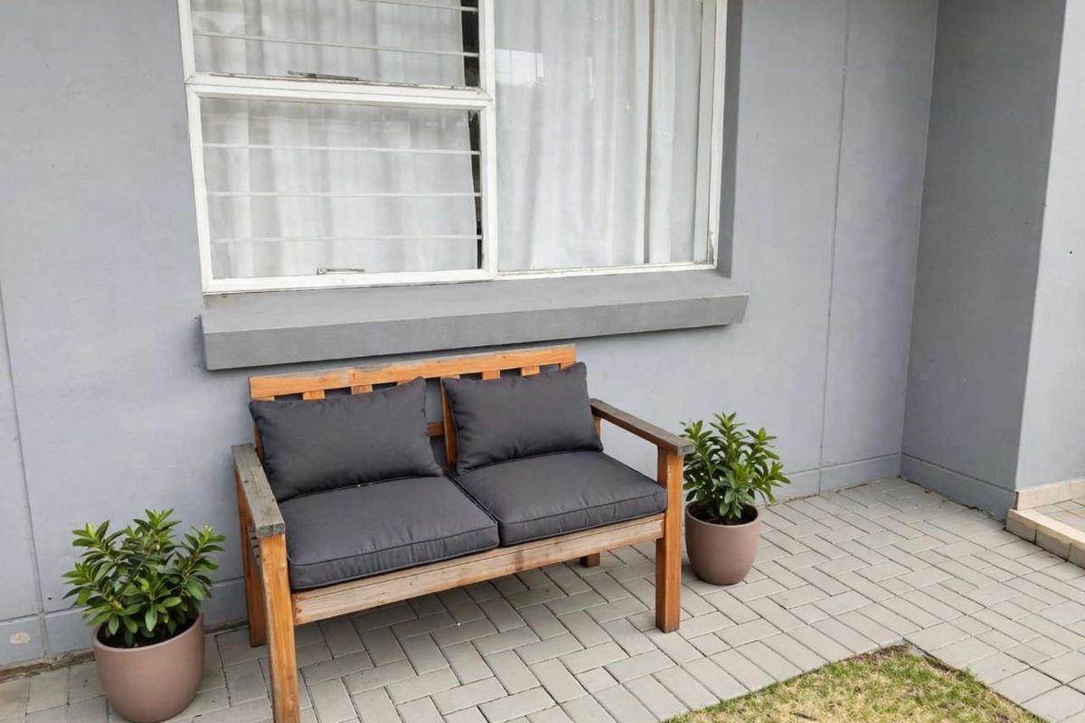 A neat paved patio area featuring a sliding window with security bars, providing a clean and functional outdoor space.
