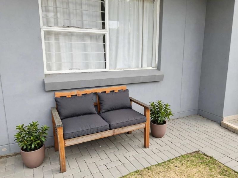 A neat paved patio area featuring a sliding window with security bars, providing a clean and functional outdoor space.