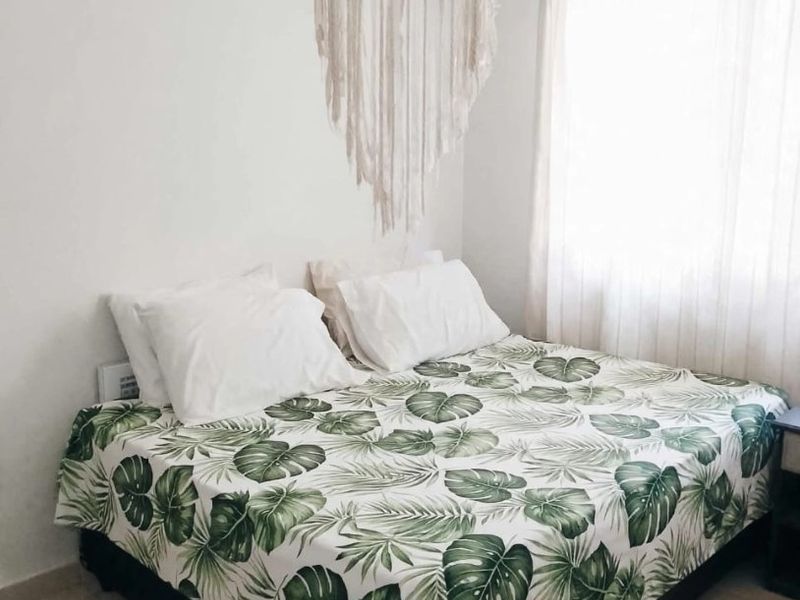 A simple bedroom featuring neutral tiled flooring and a window with curtain rails, providing a functional and well-lit sleeping space.