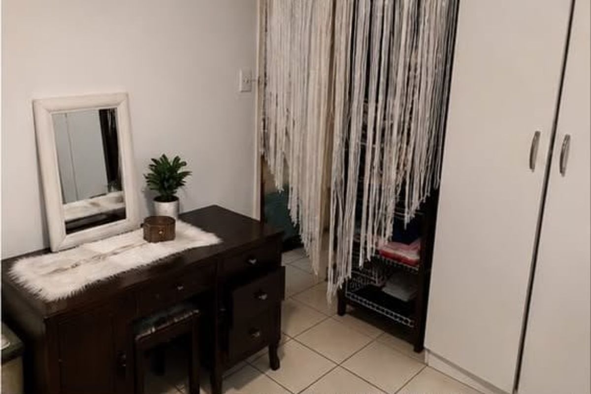 Bedroom featuring tiled flooring and a built-in wardrobe with white cabinetry.