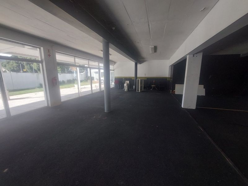 Spacious open-plan commercial area featuring large glass sliding doors, structural columns, and an exposed ceiling, offering a versatile layout for various business uses.
