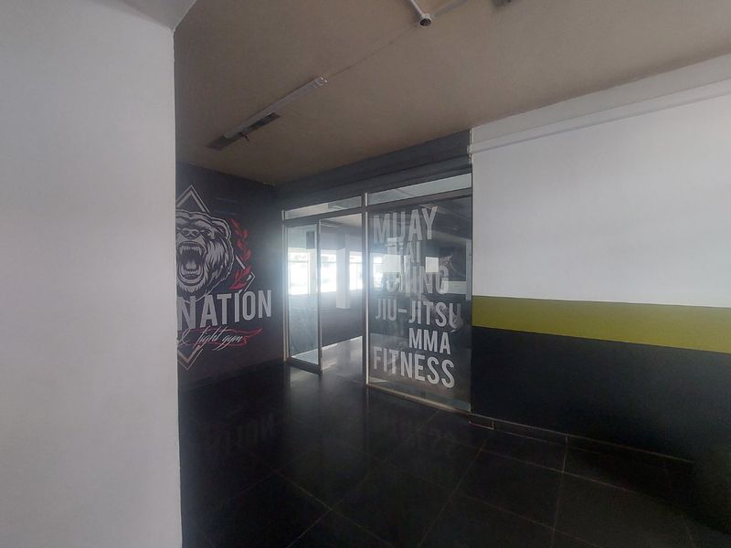 A commercial gym space featuring tiled flooring, glass partitions, and branded wall graphics, suitable for fitness or martial arts training.